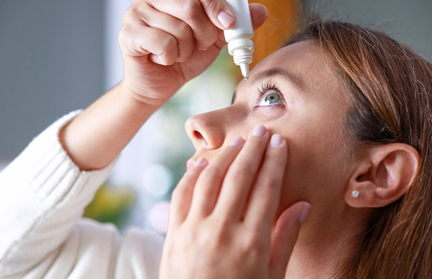 Close-up of a woman applying eye drops.