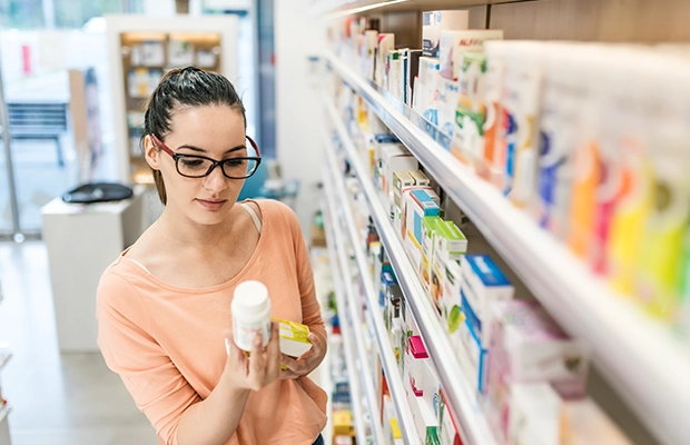 woman choosing a product from a pharmacy shelf