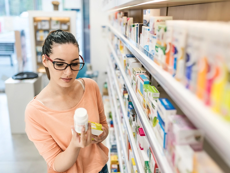 woman choosing a product from a pharmacy shelf