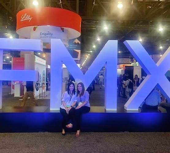 two women sitting in front of a sign