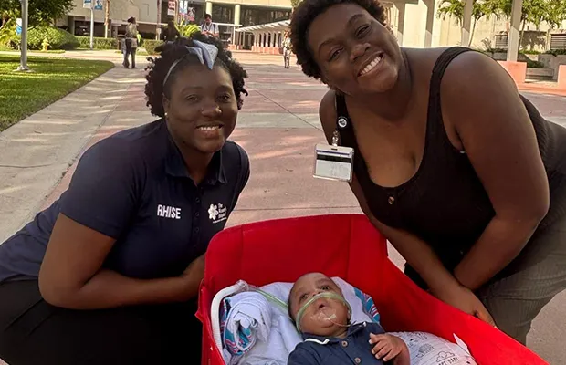 Two women posing next to a small baby
