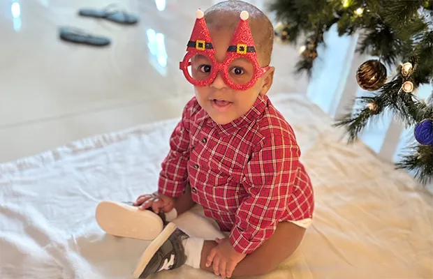 a little baby posing with Christmas glasses