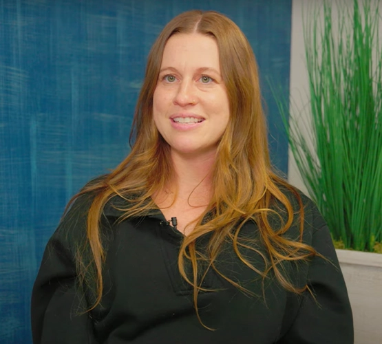 red-haired woman in a black shirt smiling at the camera