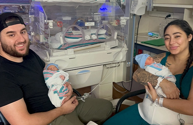 Couple holding two newborn babies.
