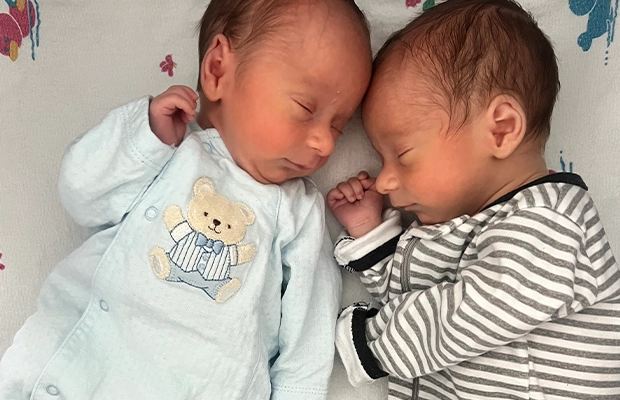 Two babies lying down facing each other.