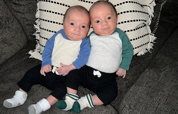 Two twin babies sitting and looking at the camera.