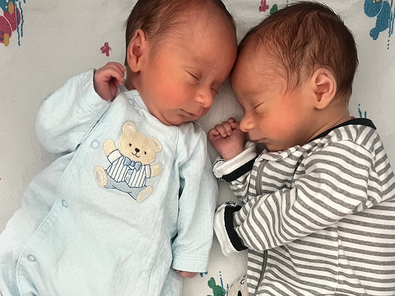 Two babies lying down facing each other.