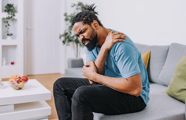 A man sitting on a sofa while feeling a strong pain in his back