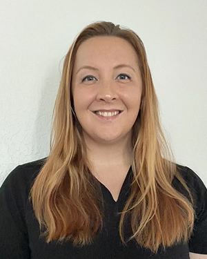 Close-up of a woman in a black shirt smiling at the camera.