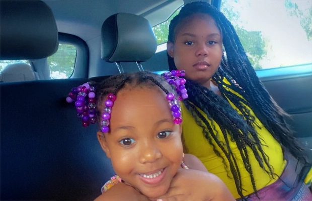 child sitting on the car next to her mom