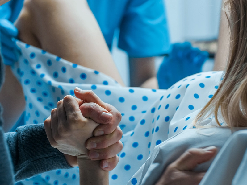 woman giving birth, while holding her partner's hand