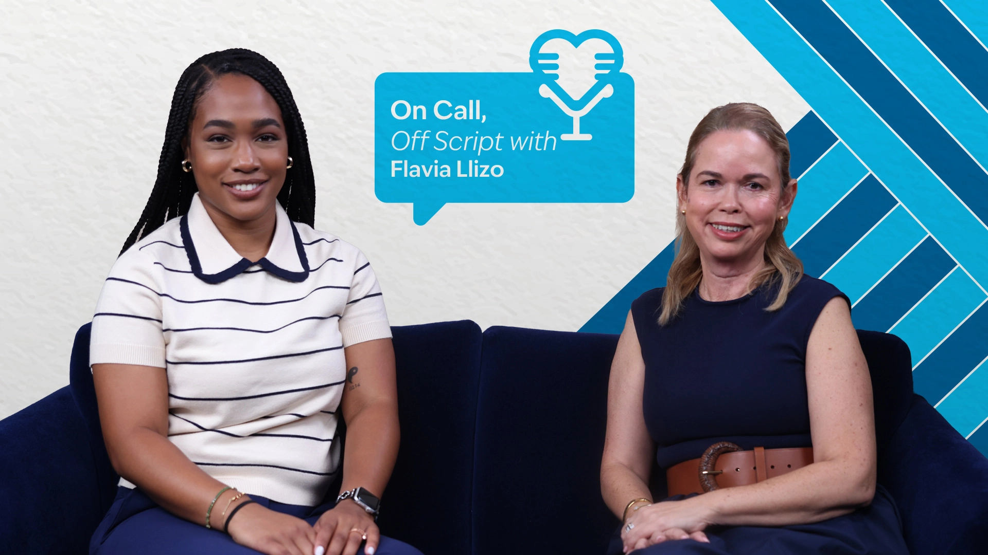 Image of two women sitting and posing for the camera, with a blue background behind them.