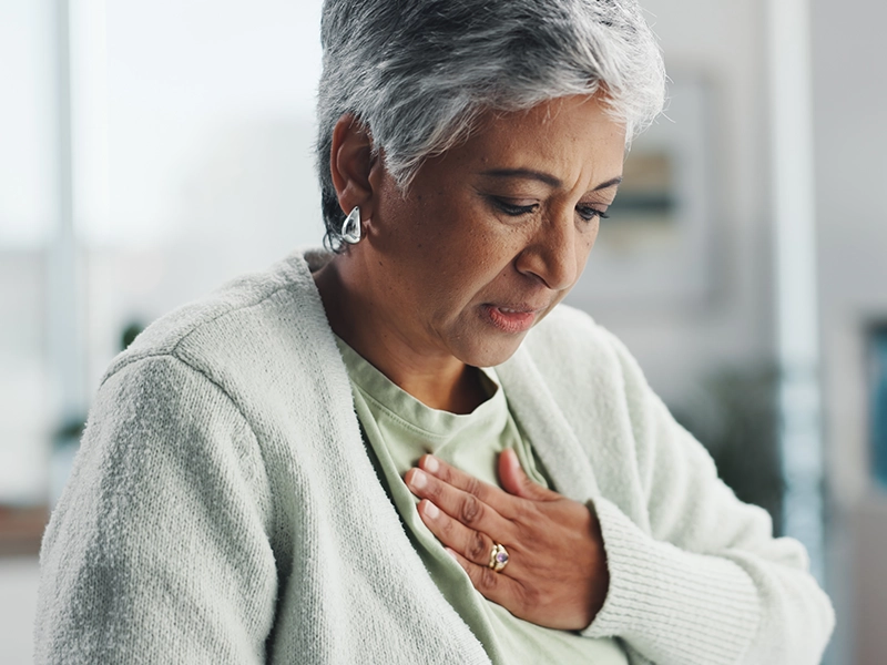 Adult woman holding her chest as if feeling severe pain.