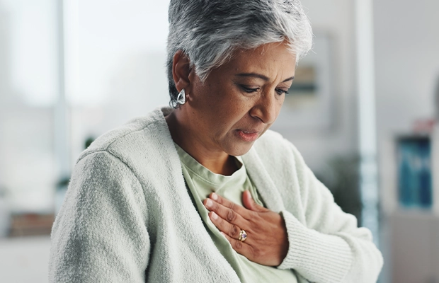Adult woman holding her chest as if feeling severe pain.
