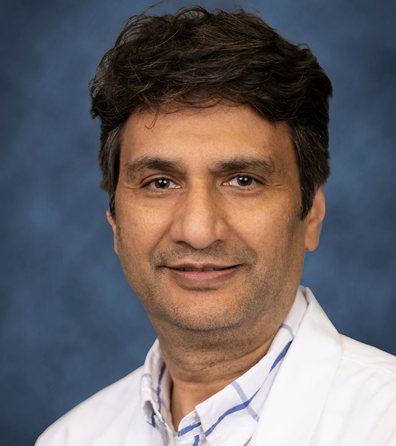 Headshot of a physician, he smiles at the camera and has on a white coat