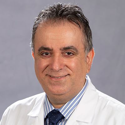 A headshot of a physician, he is smiling at the camera, he has on a white coat