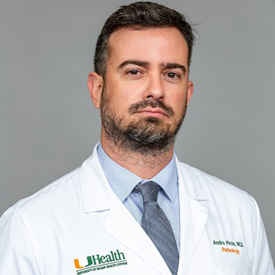 A headshot of a physician, he is looking at the camera and has on a white coat