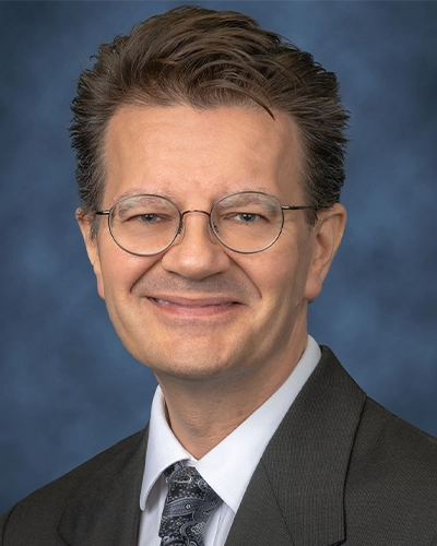 Headshot of a man, he has on glasses and is smiling at the camera