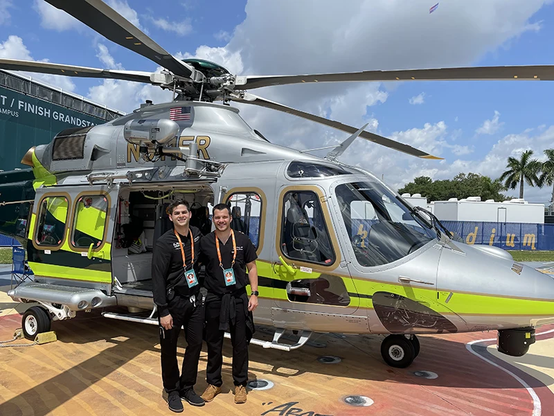 two people wearing helmet infront of a helicopter