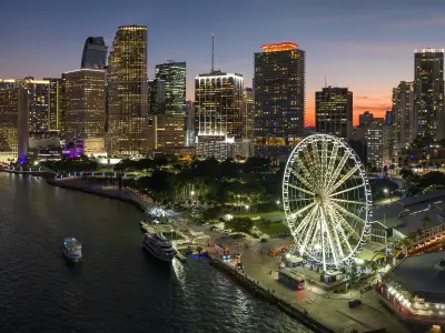 view of a city at night where you can see a ferris wheel around buildings
