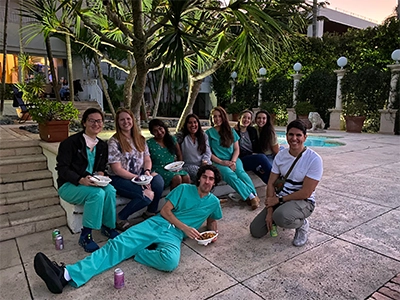 group of doctors sitting on the ground in the park while having a snack