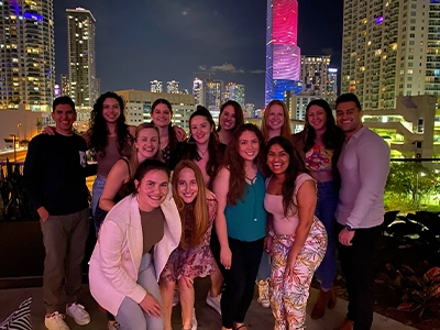 group of people posing at night surrounded by illuminated buildings