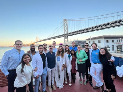 group of doctors posing and smiling at the camera next to a bridge