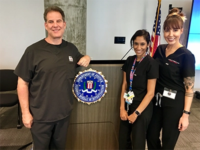 three people posing and smiling at the camera