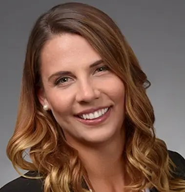 A closeup of a woman, she has long light hair and smiles at the camera