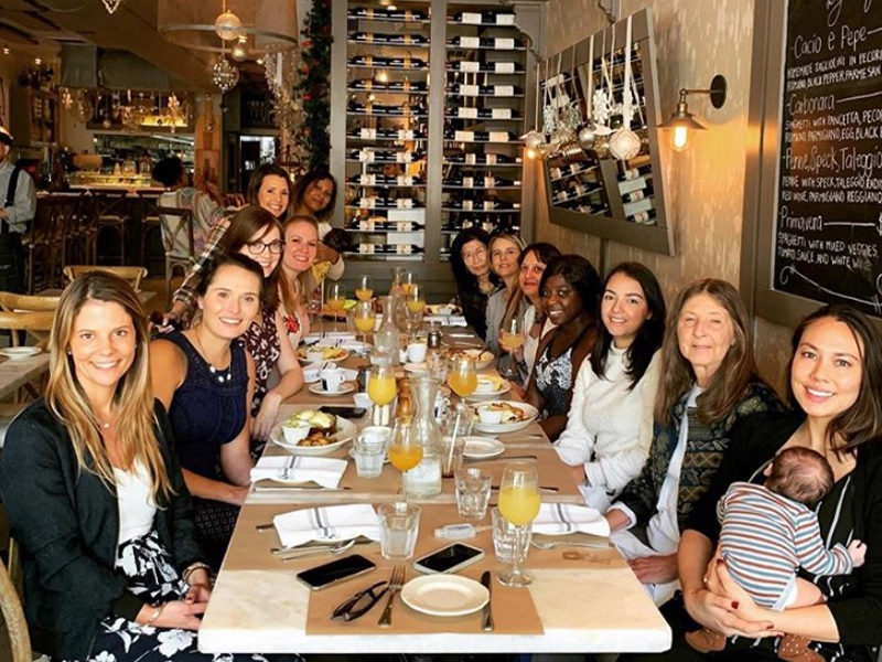 Group of women posing and smiling at the camera while having a dinner