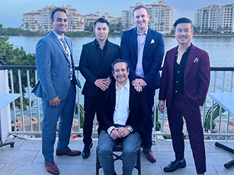 Group of five men, they are looking at the camera, they are waring suits, they are outdoors