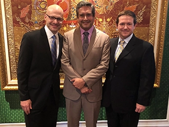 Group of three men, they are standing next to each other and looking at the camera, they are waring suits