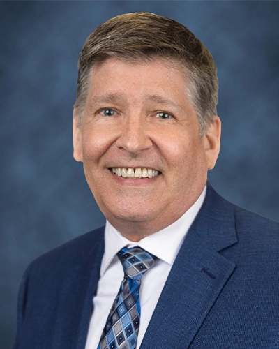 Headshot of a man, he is looking at the camera and smiling