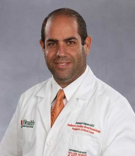 A medical professional, he is wearing a white coat and smiles at the camera