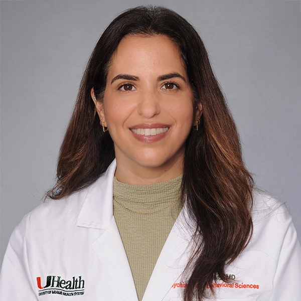 Headshot of a physician, she has long dark hair and smiles at the camera