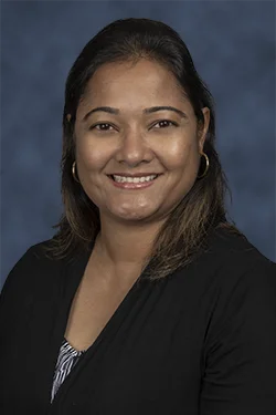 A headshot of a woman with shoulder length dark hair, she smiles at the camera