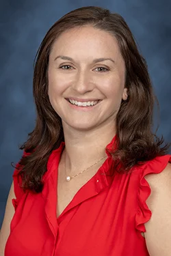 A headshot of a woman with shoulder length hair, she smiles at the camera