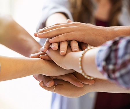 Closeup of multiple hands, each hand is over another