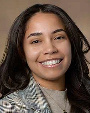 Close-up of a woman in a plaid suit smiling at the camera.