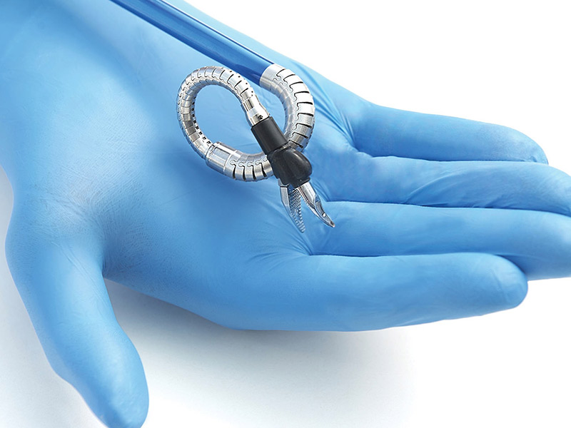 Closeup of a gloved hand, the hand is open and holding a small device