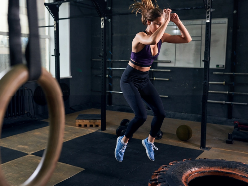 Photograph of a woman jumping in a gym.