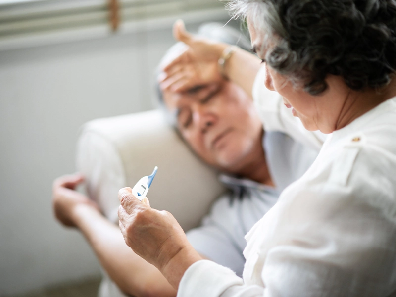 Nurse taking temperature of elderly patient