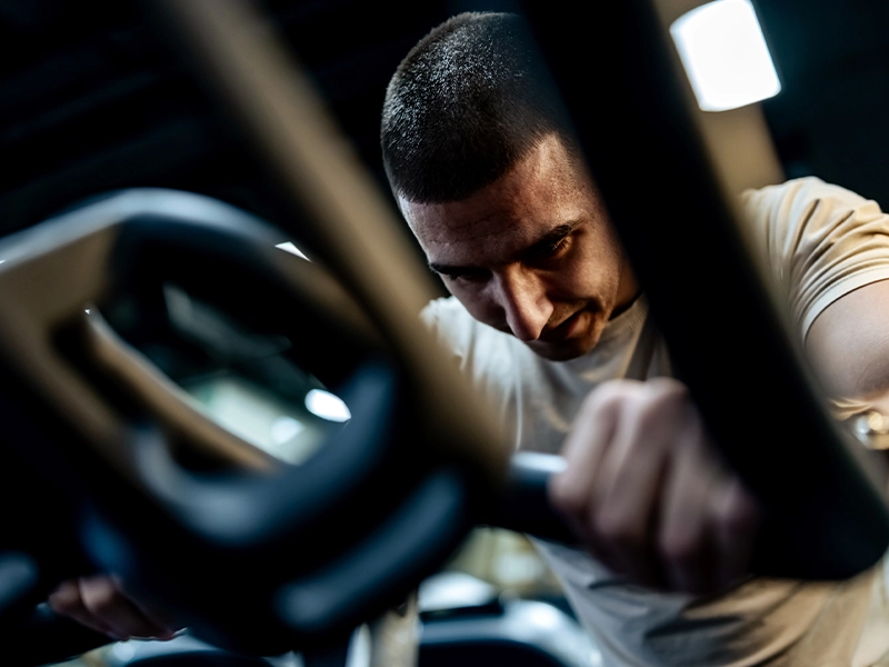 Close-up of a man exercising on a gym machine.
