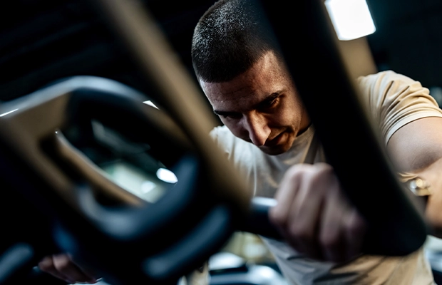 Close-up of a man exercising on a gym machine.