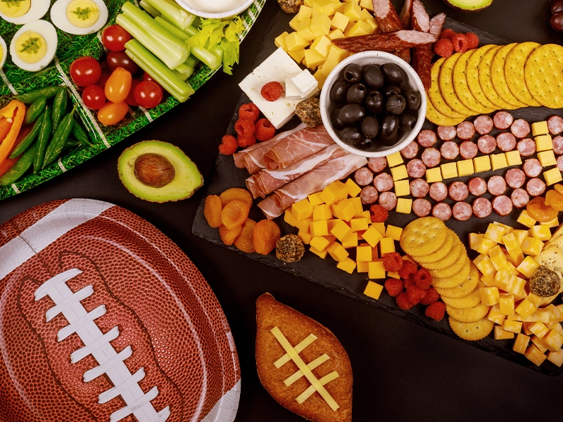 An image showing various healthy foods, such as vegetables, eggs, and crackers, and even a dessert shaped like an American football.