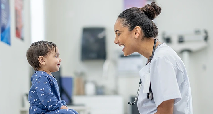 A medical professional smiling as she looks at a young patient