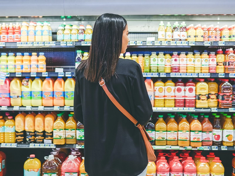 woman choosing a drink in front of the supermarket refrigerators