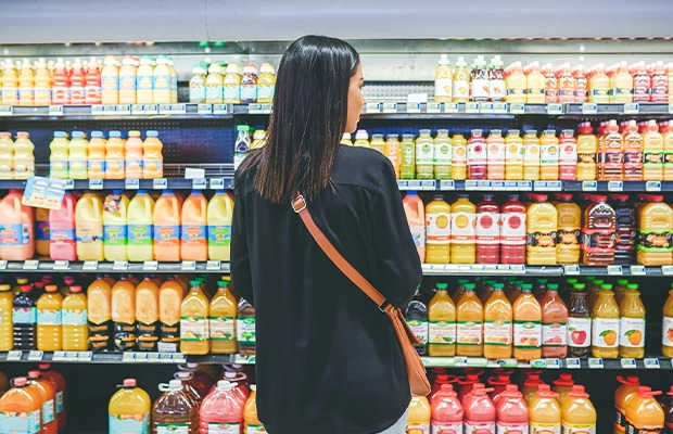 woman choosing a drink in front of the supermarket refrigerators