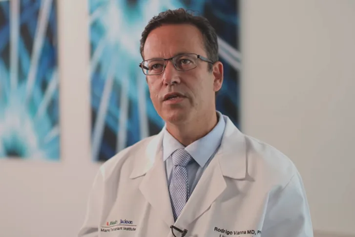 A medical professional speaking, he has on a white coat and glasses