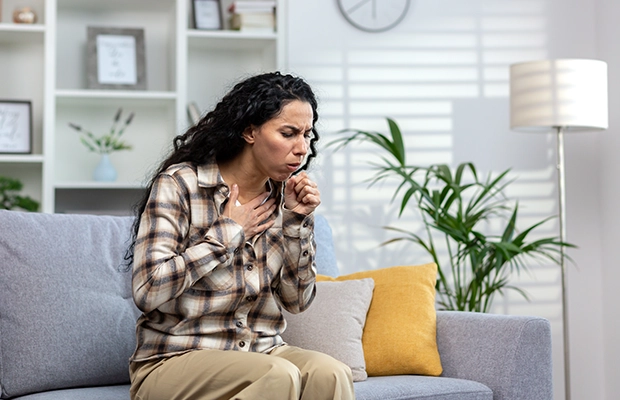 woman sitting on a sofa while coughing